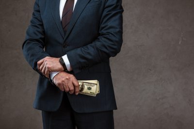 cropped view of businessman holding dollar banknotes in hand on grey