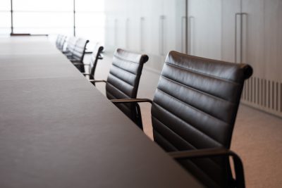 A row of brown leather chairs at an empty conference table